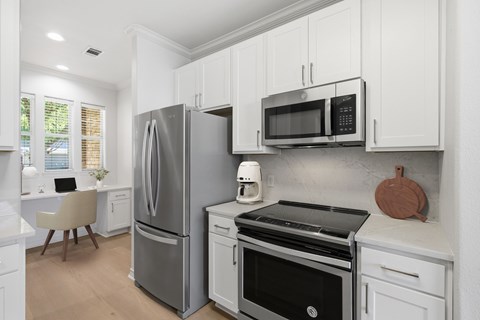 A modern kitchen with white cabinets and stainless steel appliances.