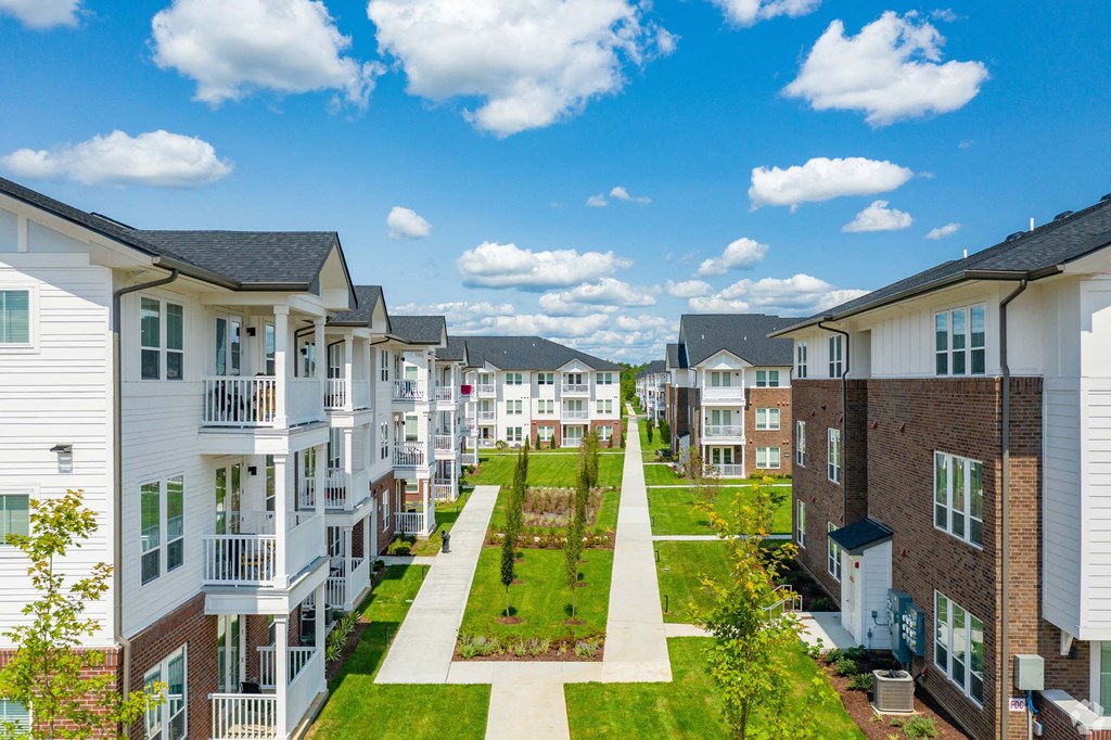 A row of modern townhouses with a green lawn in the foreground.