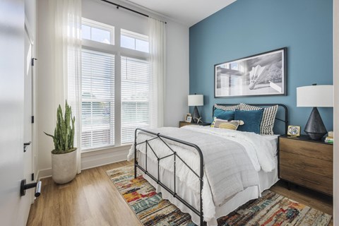 A bedroom with a bed, nightstands, and a plant.