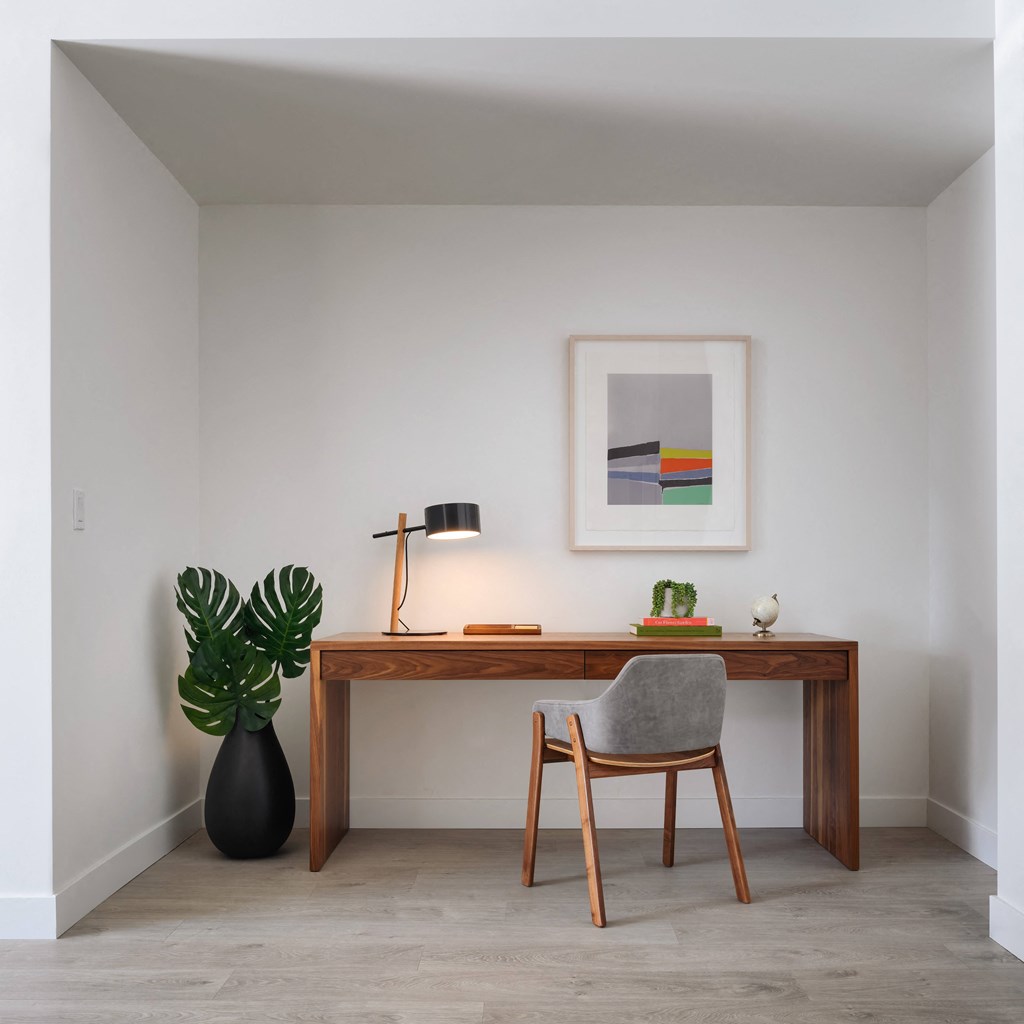 a desk with a chair and a plant in a room