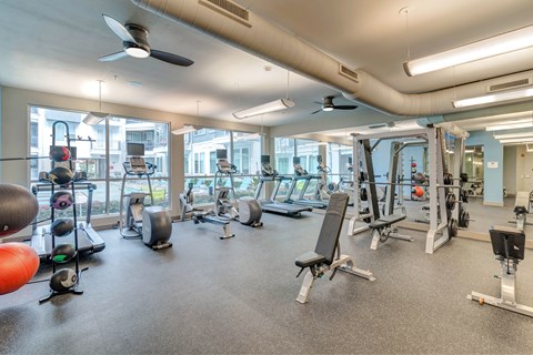 A spacious gym with various exercise equipment and a fan.