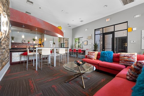 A living room with a red couch and a glass coffee table.