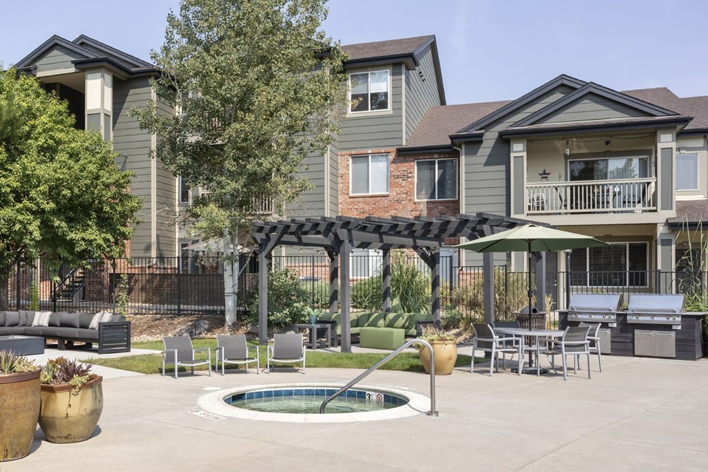 A patio with a hot tub and chairs is surrounded by houses.