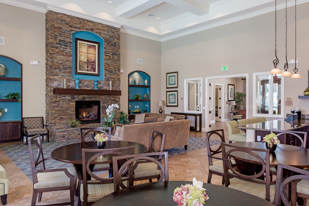 A room with a stone fireplace and a dining table set for six.