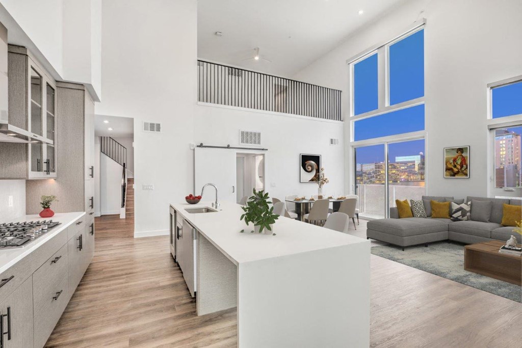 a kitchen and living room with white walls and wood floors