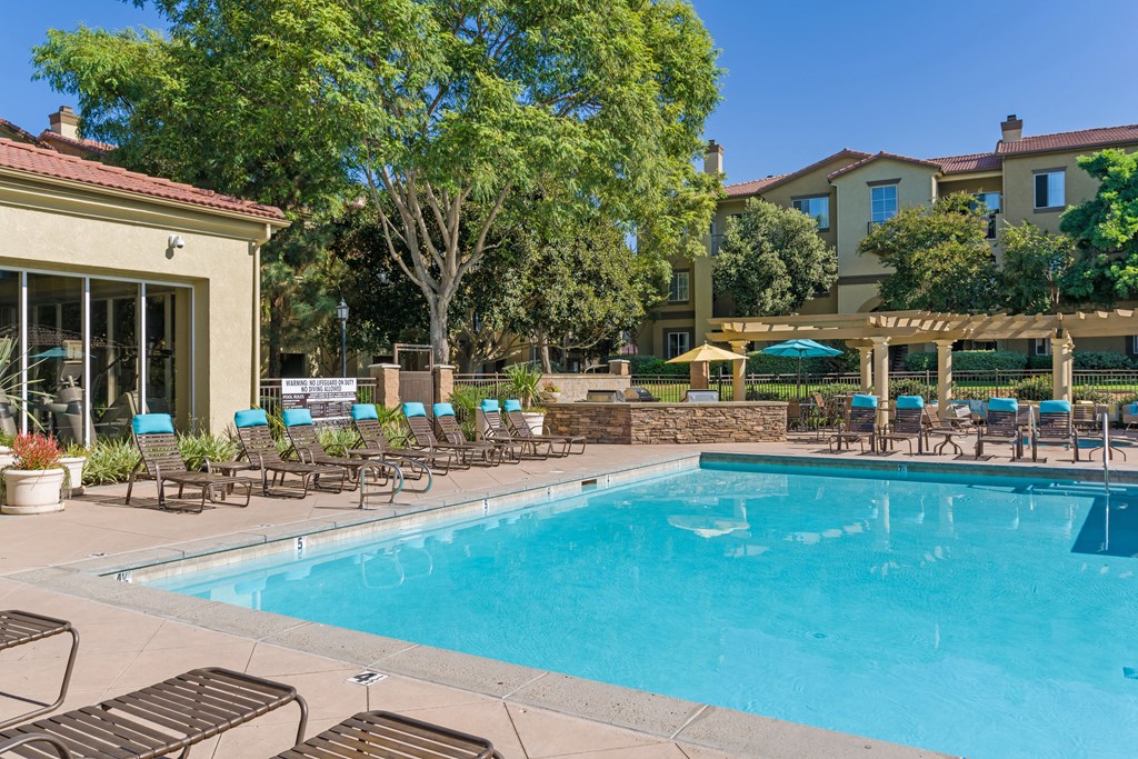A large swimming pool surrounded by lounge chairs and trees.