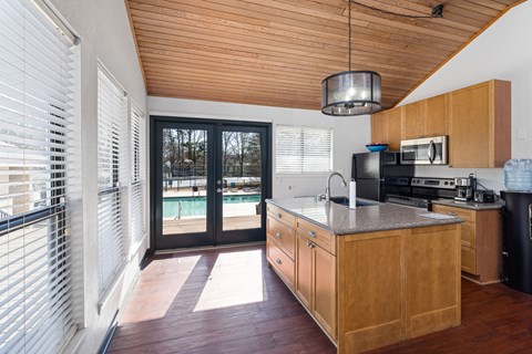 A kitchen with wooden cabinets and a black trash can.