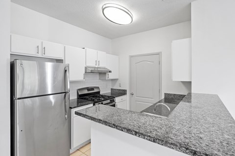 A kitchen with a granite countertop and stainless steel appliances.