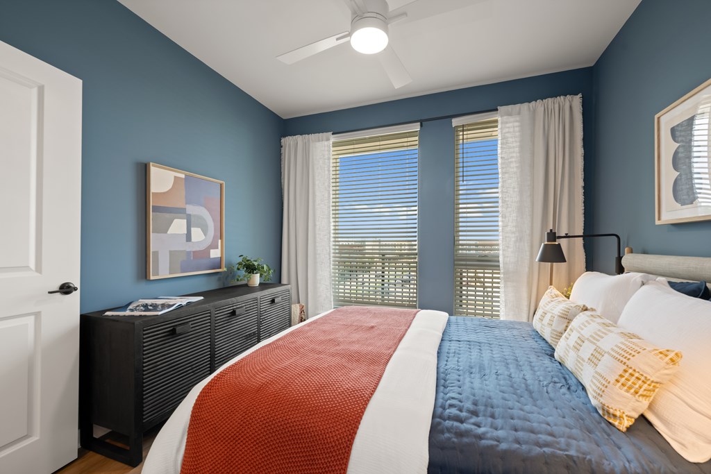 A bedroom with a bed, dresser, and window.