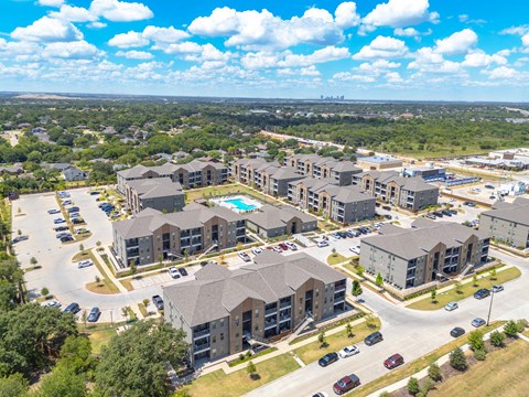 an aerial view of an apartment complex with a pool and parking lot