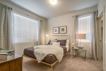 A bedroom with a bed, nightstand, and window.