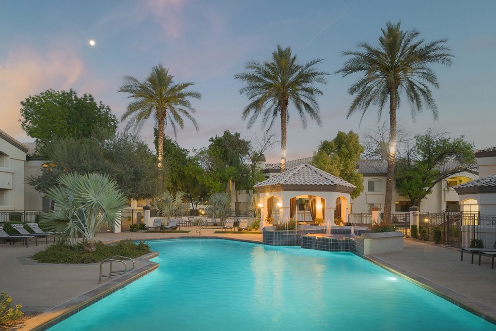 a large swimming pool with a gazebo and palm trees in the background
