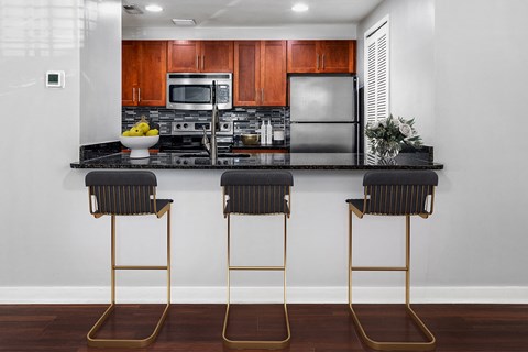 A kitchen with a black counter top and two black barstools.