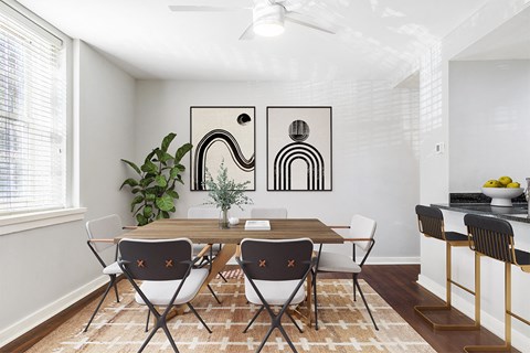 A dining room with a table set for two and a plant in the corner.
