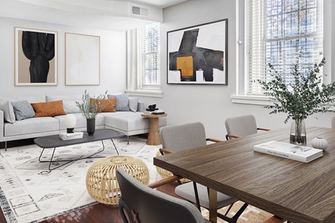 A modern living room with a grey sofa, a wooden table, and a woven chair.