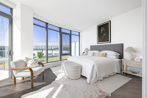 A bedroom with a large bed and a chair by the window.