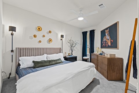 A bedroom with a bed, nightstand, and a painting on the wall.