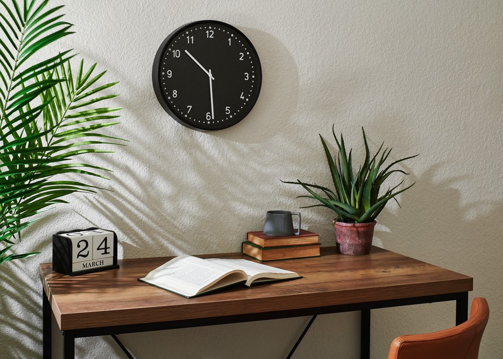 a desk with a clock and plants on top of it