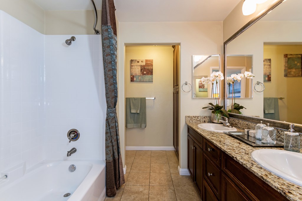 A bathroom with a white tub and brown countertops.