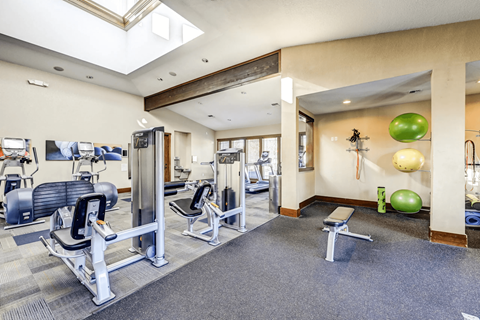 A gym with a variety of equipment including weights and exercise balls.