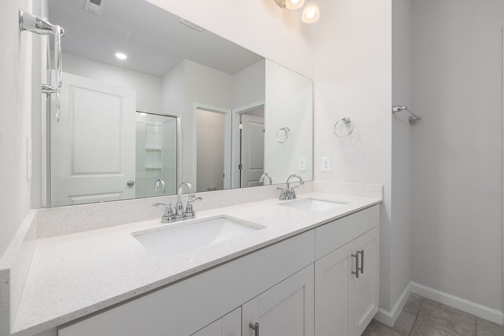 a white bathroom with two sinks and a large mirror