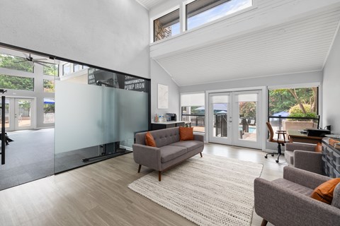 A living room with a grey couch and a glass wall.