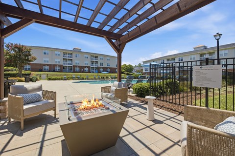 A patio with a fire pit and chairs.
