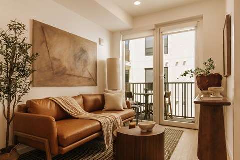 A living room with a brown leather couch and a large abstract painting on the wall.