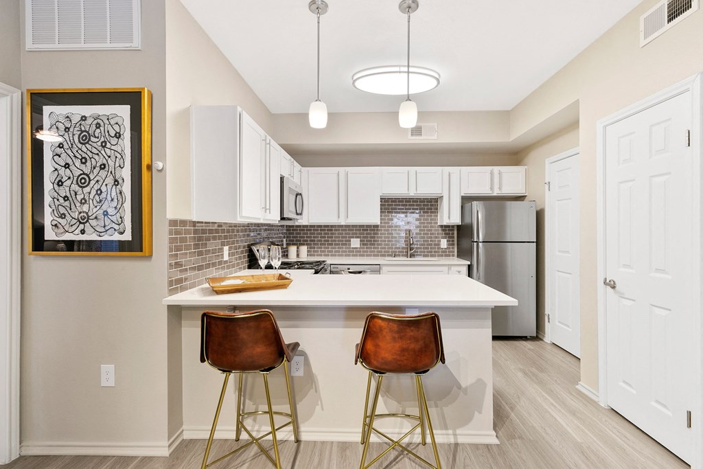 a kitchen with a white counter top and three stools