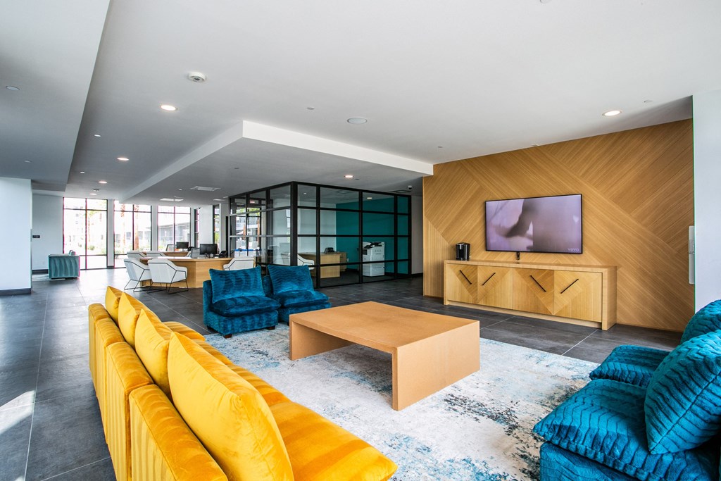 a living room with yellow couches and blue chairs and a television