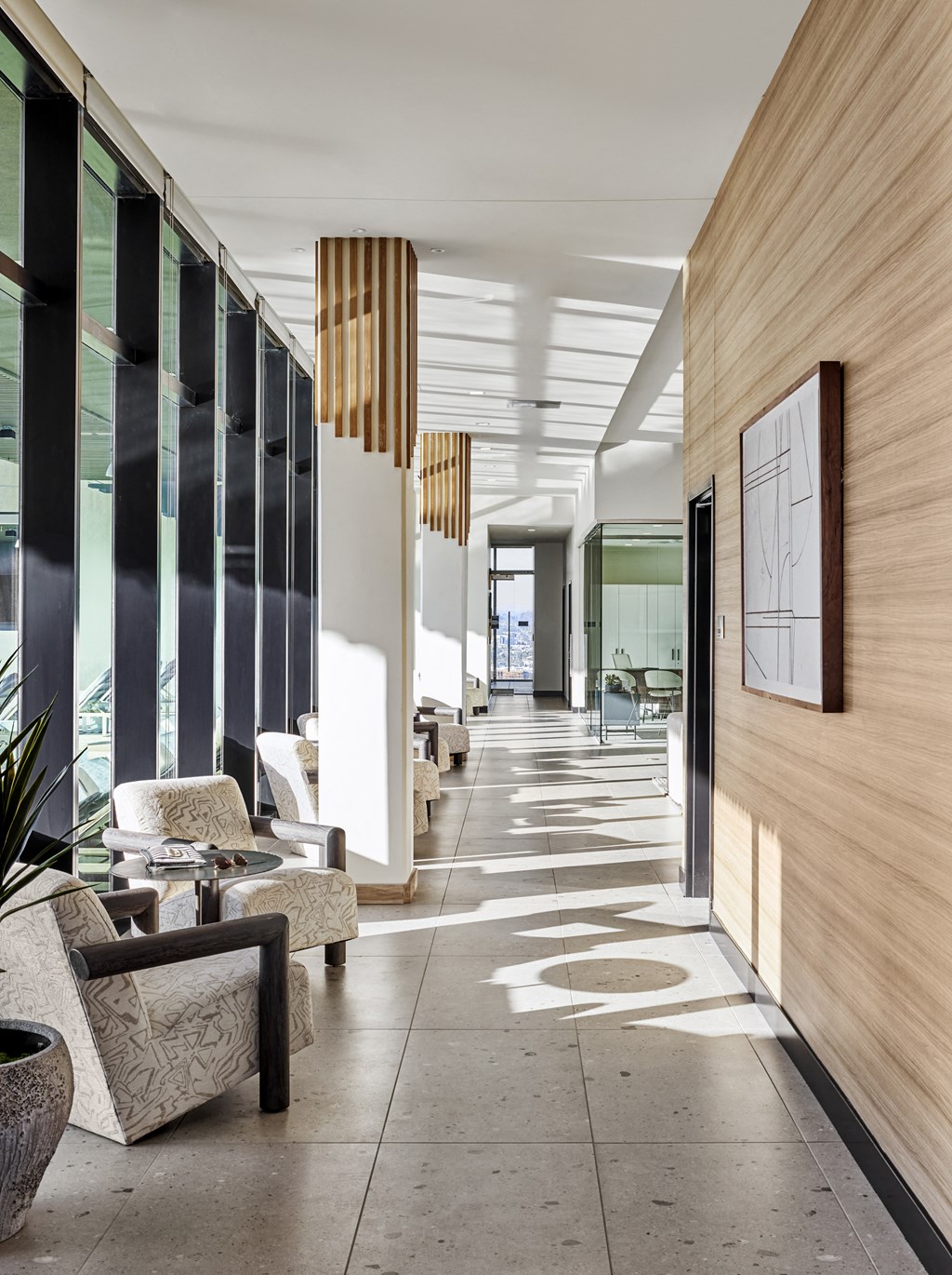 a lobby with chairs and tables and a large wood wall
