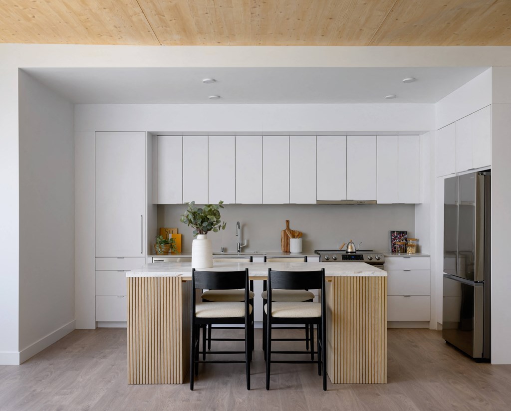 a kitchen with white cabinets and a table with black chairs