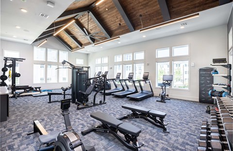 a gym with cardio equipment and windows in a building