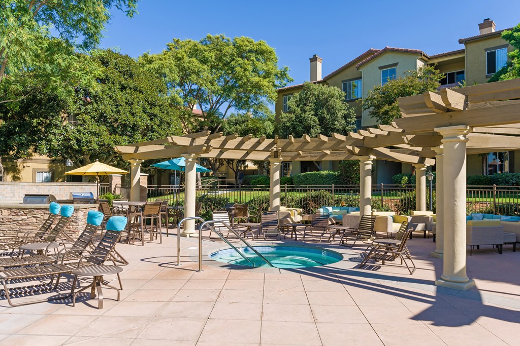 A pool area with sun loungers and a pergola.
