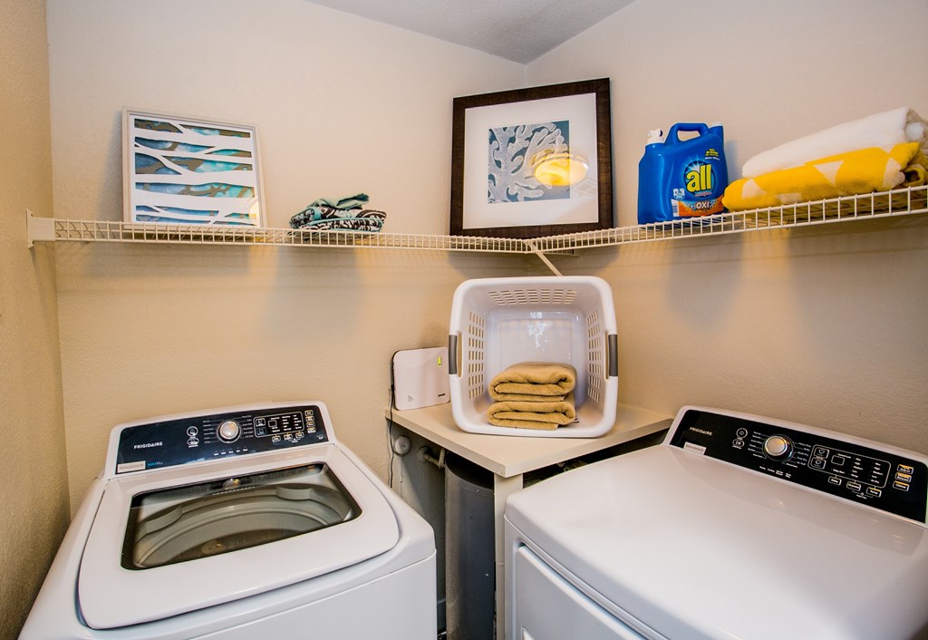 A laundry room with a washer and dryer and a basket of towels.