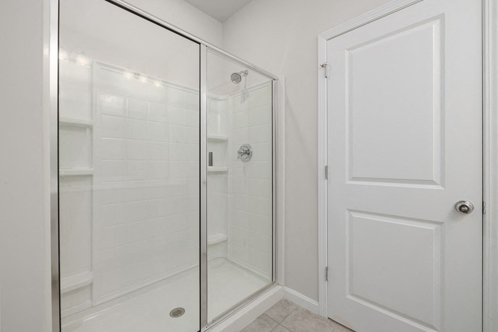 a white bathroom with a shower and a door