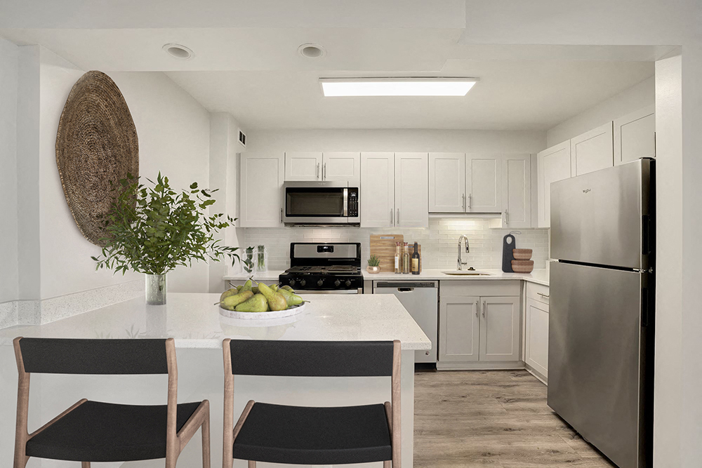 a white kitchen with stainless steel appliances and a white table and chairs