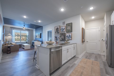 A kitchen with a refrigerator on the right and a dining table with chairs in the middle.