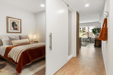 A bedroom with a bed, a chair, and a painting on the wall.