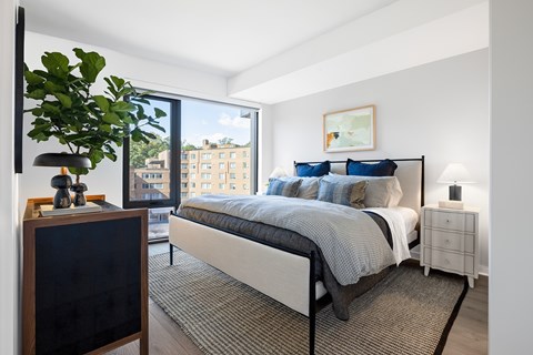 A bedroom with a large bed and a view of a building outside the window.