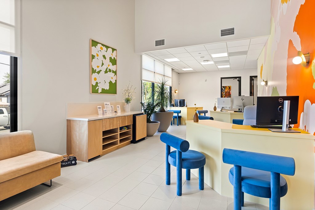 A reception area with blue chairs and a wooden counter.