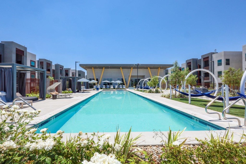 A large swimming pool surrounded by lounge chairs and umbrellas.