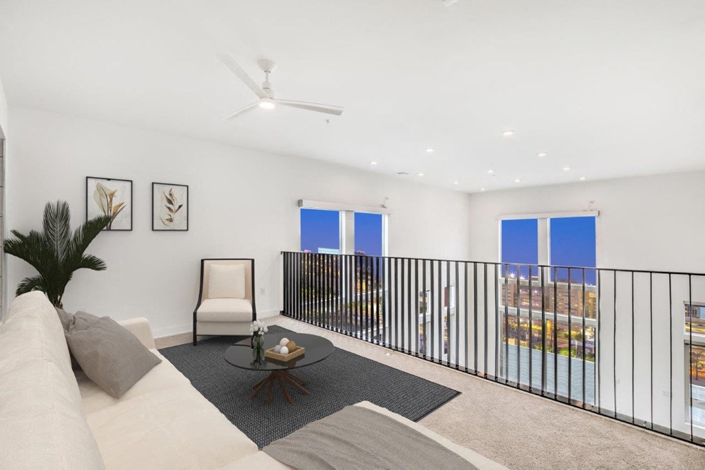 a lofted seating area with white walls and a black railing