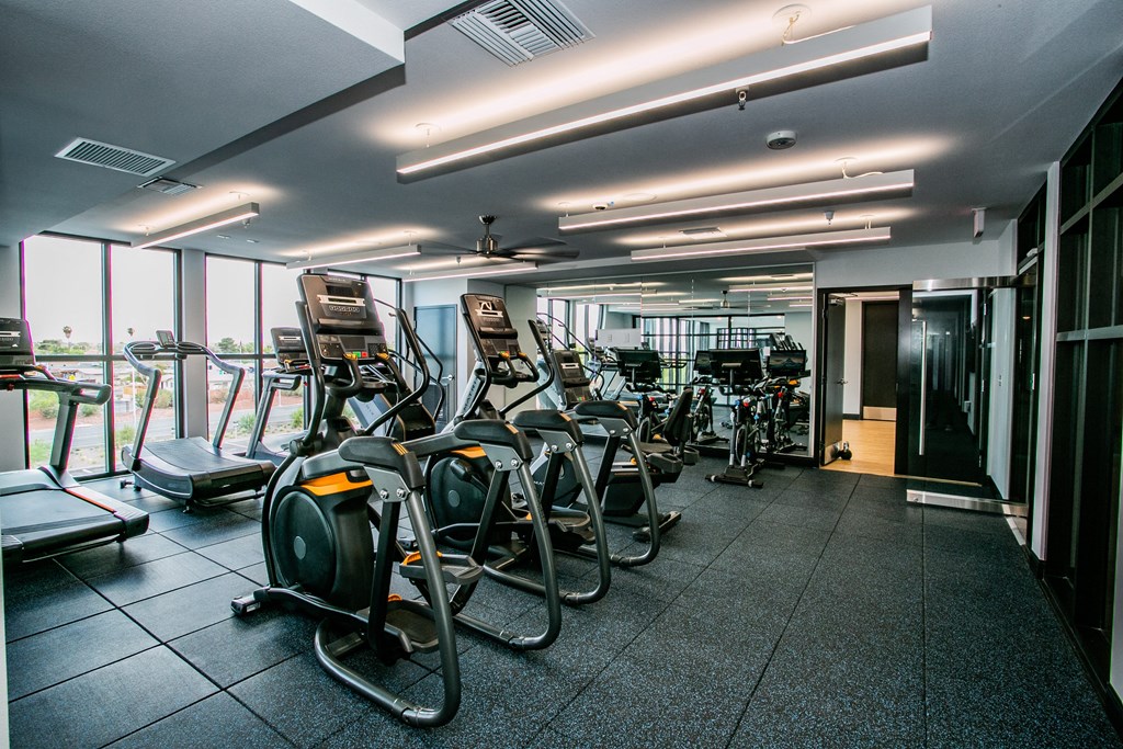 a gym with cardio machines and a large window