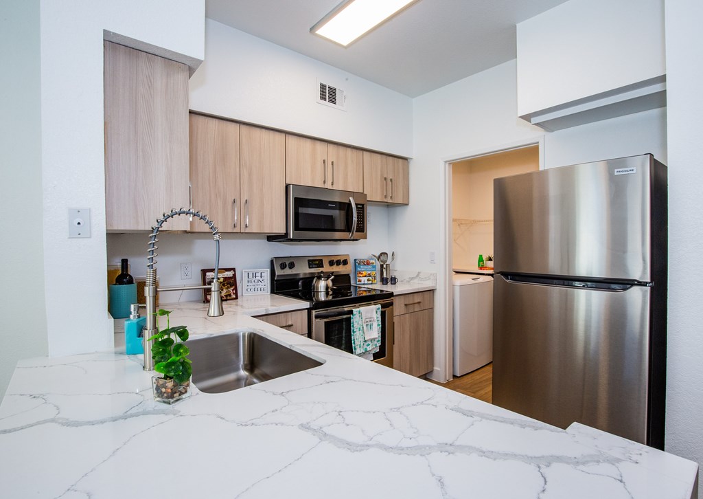 A kitchen with a stainless steel refrigerator and a marble countertop.