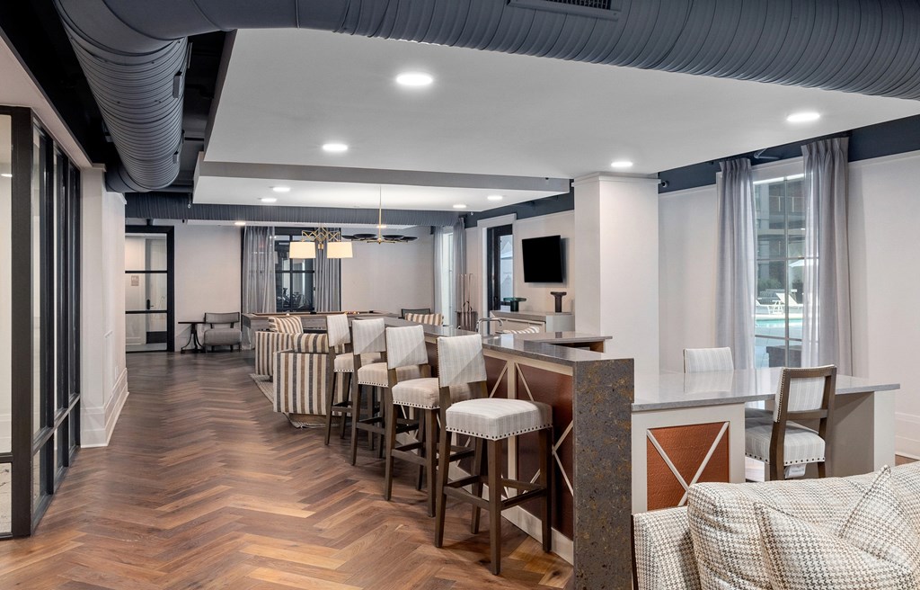A modern bar area with wooden floors and white walls.