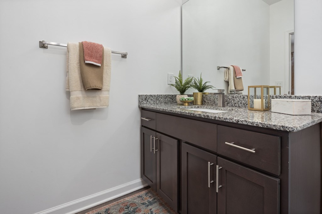 A bathroom with a white counter top and brown cabinets.