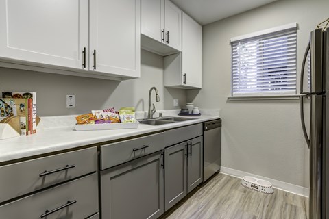 A kitchen with white cabinets and a refrigerator.