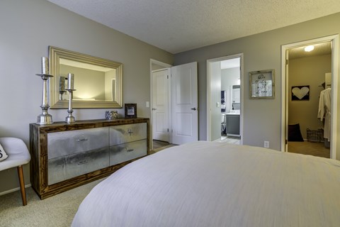 A bedroom with a large bed and a dresser with a mirror.