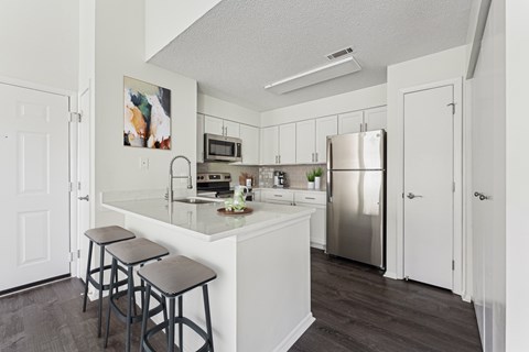 A kitchen with a white counter top and a refrigerator.
